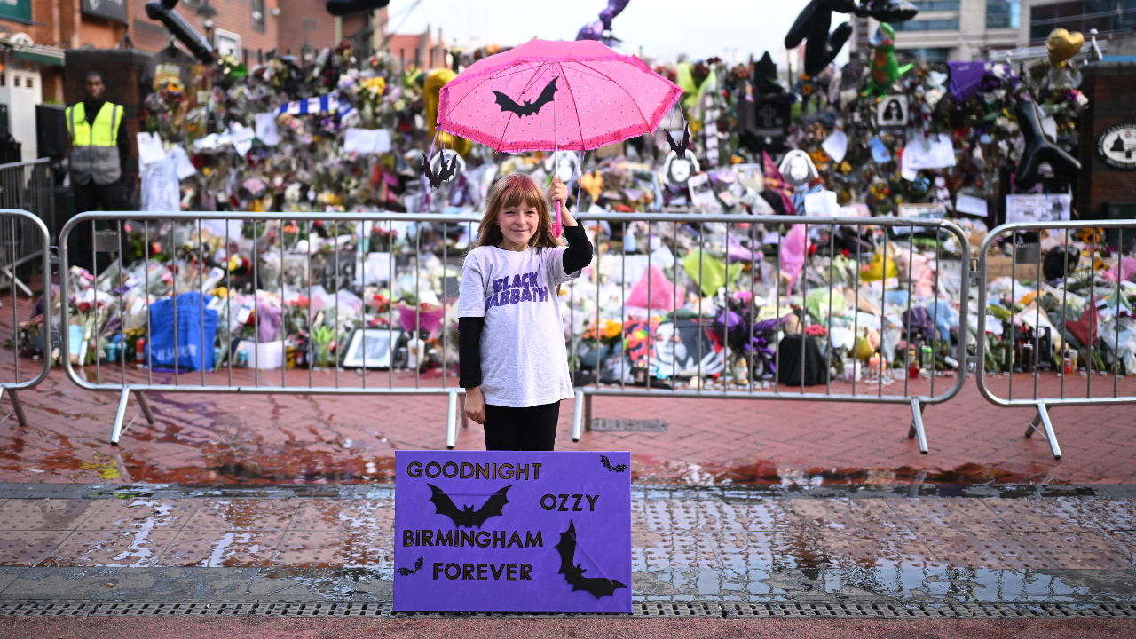 A young girl at the Ozzy funeral procession with a sign that says: Goodnight Ozzy