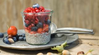 Chia seed pudding in glass jar with strawberries, cranberries, blueberries on top