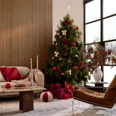 Living room with Christmas tree, red cushion on sofa and lit candles on coffee table