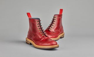 A pair of red leather ankle boots with black laces and brown soles.