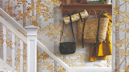 An autumnal tree-print wallpaper mural in a hallway with a peg rail and a staircase