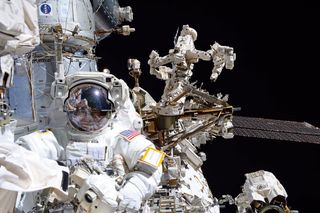 NASA astronaut Mark Vande Hei on a spacewalk, backdropped by the Canadian Dextre "handy robot."