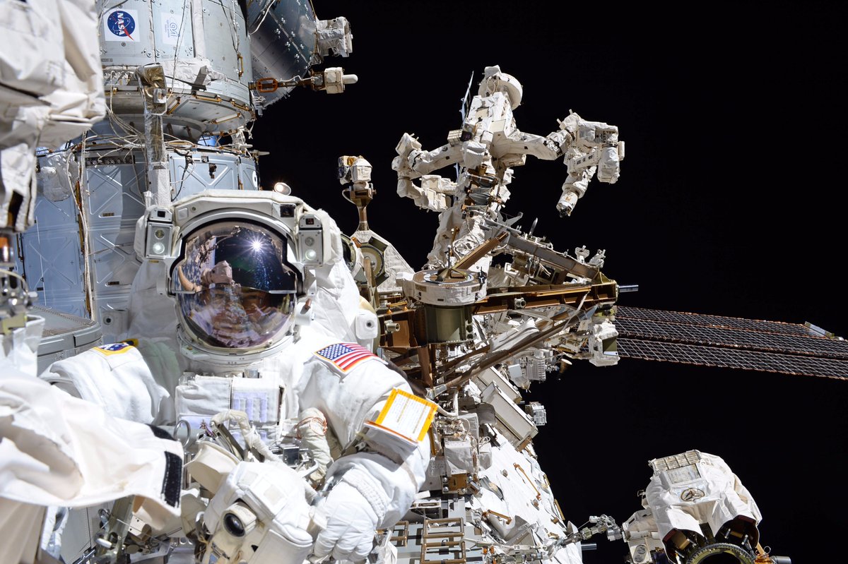 astronaut in a spacesuit in front of dextre robot on the international space station