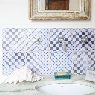 bathroom sink with blue and white patterned tile splashback and marble sink top