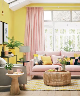 Sunny yellow walls, and blush sofa with yellow pop cushions, and coordinating full length blush drapes.