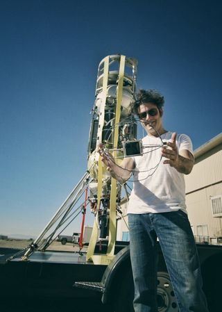Lunar Exocam principal investigator Jason Achilles Mezilis, pictured with a prototype Lunar ExoCam module and Masten Space Systems' Xodiac vehicle.
