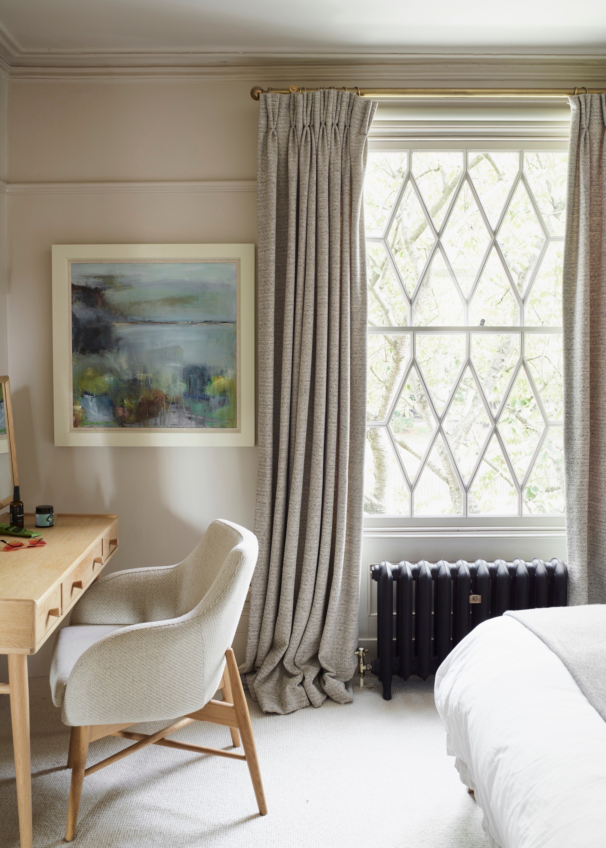 pale coloured bedroom with leaded windows and grey curtains
