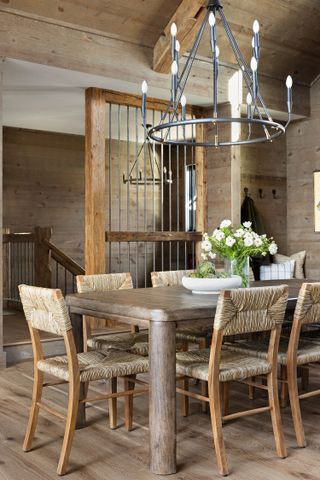 dining room with rustic wood table and wooden panels woven seats and chandelier above
