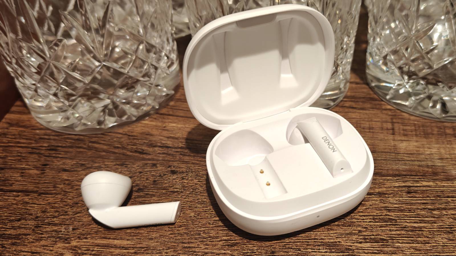 The Denon AH-C500W's bud next to the case with the other bud inside.