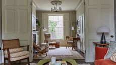 Living room with doubel doors, orange sofa, wood chairs, wood desk, woven armchairs and large carpet