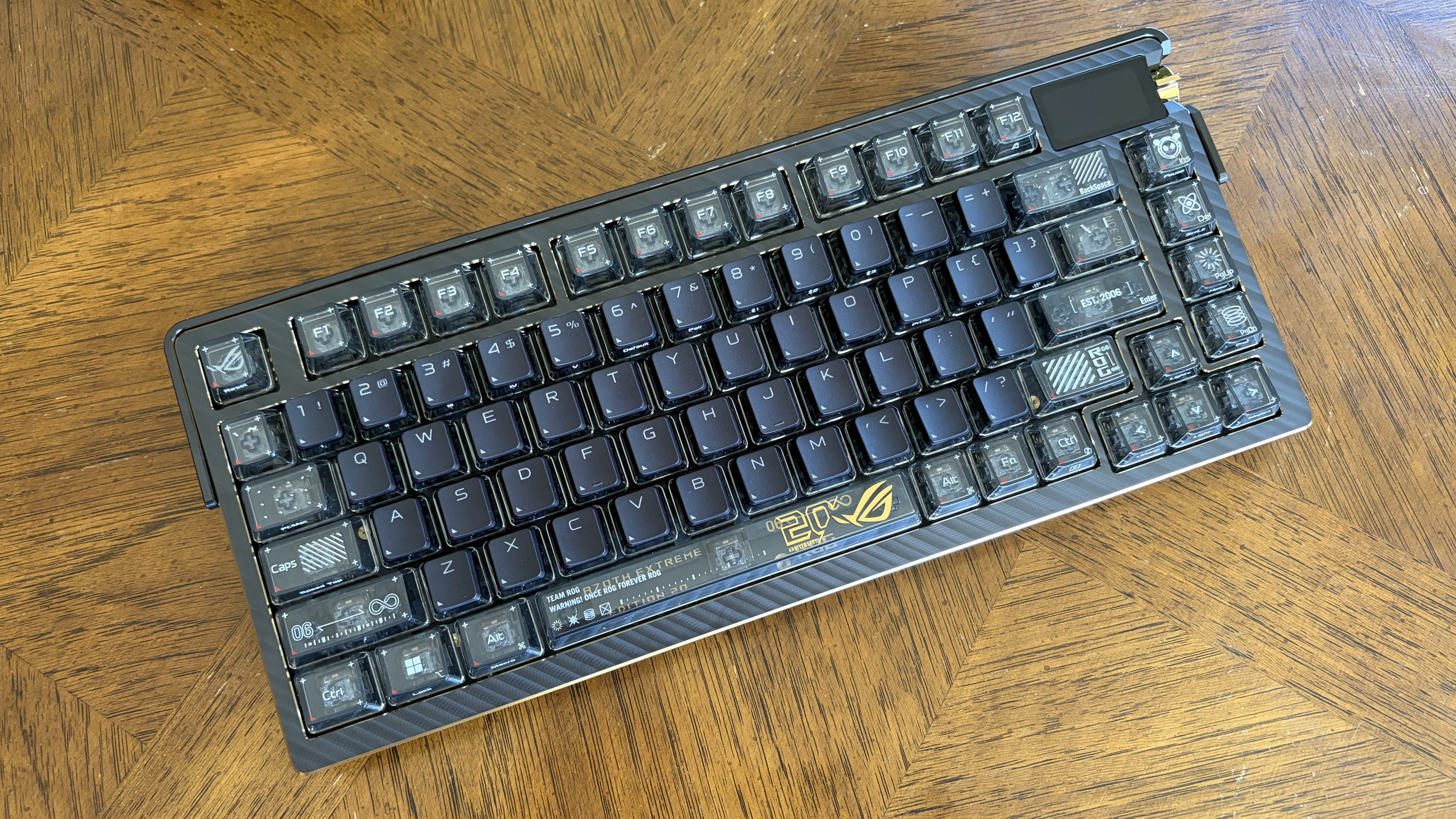Compact black ASUS ROG Azoth Extreme Edition 20 mechanical keyboard with transparent key edges on a wooden table.