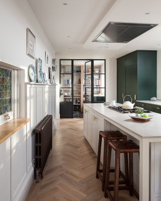 Contemporary kitchen ideas by Holloways, with white cabinetry, dark green accents and herringbone wood flooring.