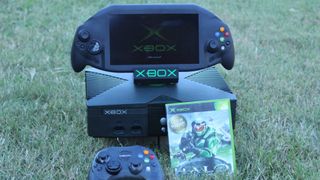 Original Xbox handheld displayed with the original console, a copy of Halo: Combat Evolved and a controller