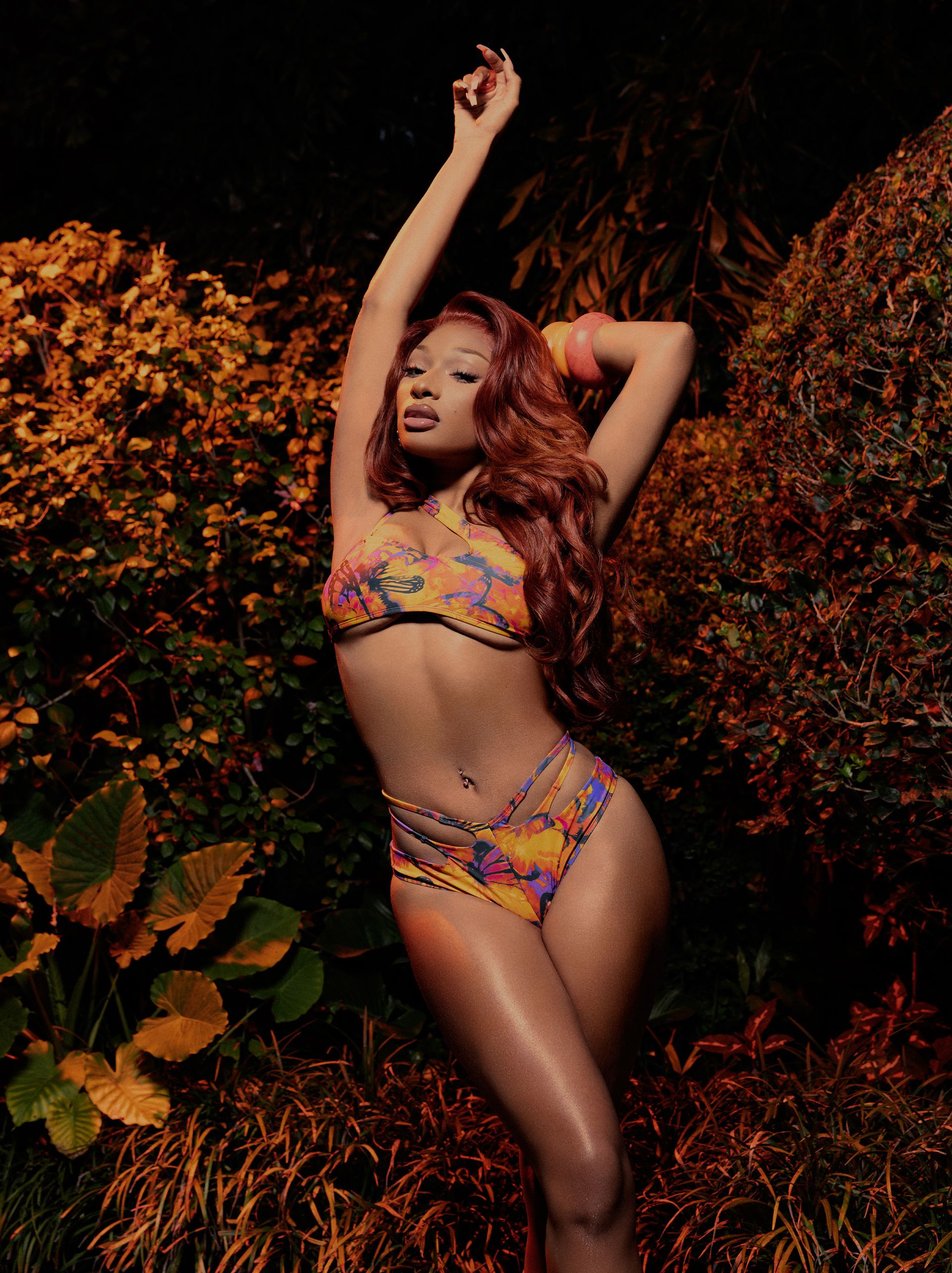 Megan the Stallion wearing a printed bikini in front of shrubbery.