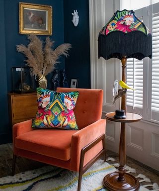 window treatment ideas for period homes, cosy nook in living room with orange armchair, blue walls, fringed lamp, half shutters,