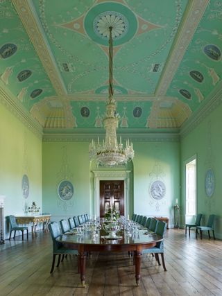 Green dining hall with painted ceiling and glass chandelier