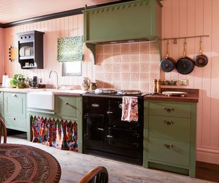 green painted kitchen cabinets with scalloped trim and pink walls