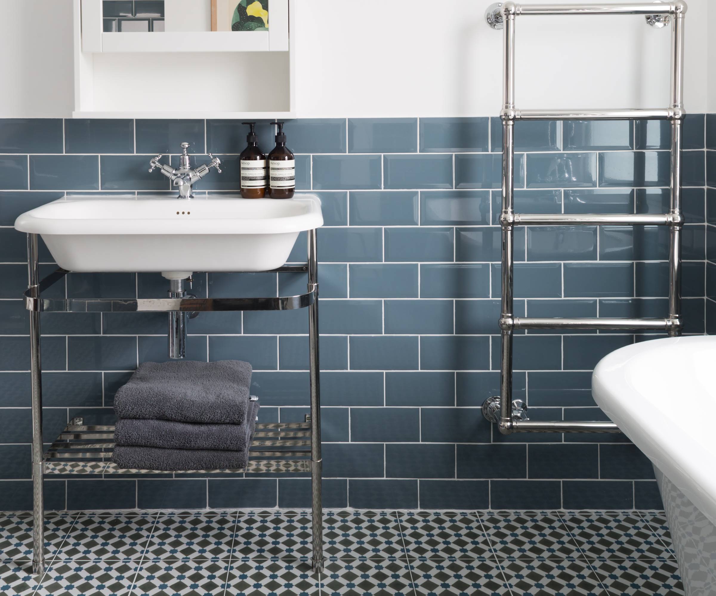 Blue tiled bathroom with vanity basin and towel rail