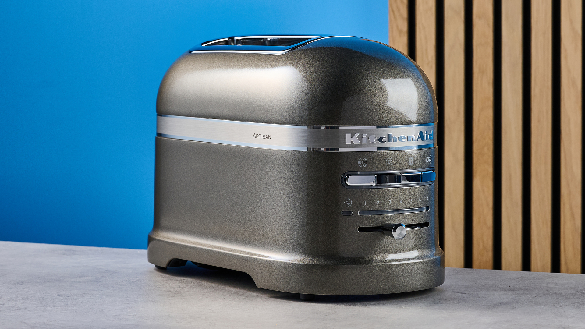 A photograph of the KitchenAid Pro Line toaster on a stone work surface with a blue and wooden background