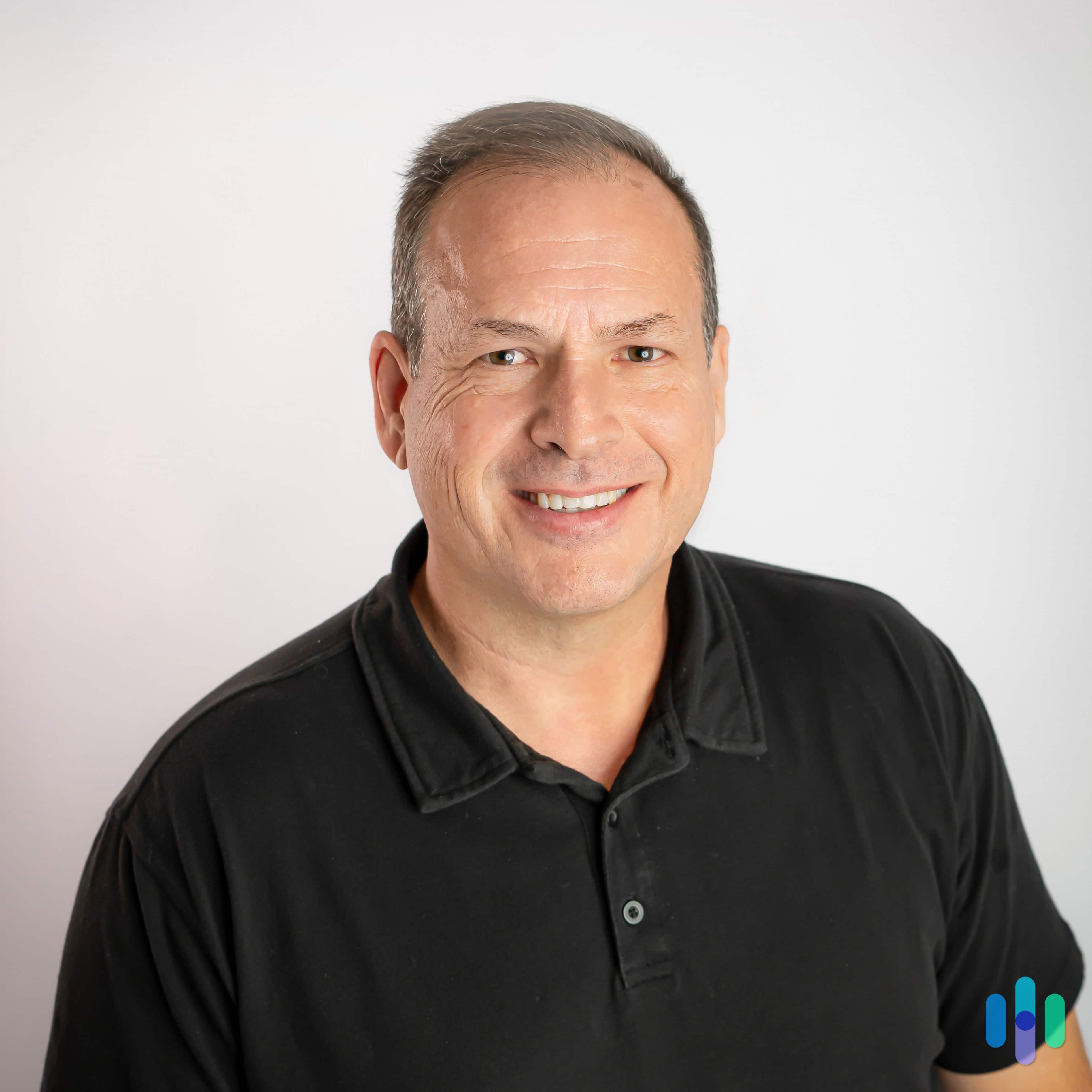Headshot of Gene Petrino, smiling, in black polo shirt against white background.