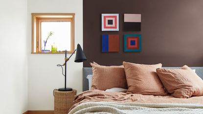 a bedroom with a brown and white painted wall, and geometric artworks 