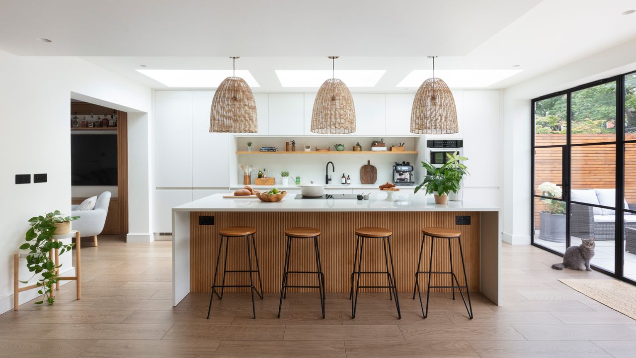 Scandi-style white kitchen with breakfast bar and large oversized pendants and patio doors 