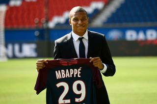 Kylian Mbappe poses with a Paris Saint-Germain shirt at the Parc des Princes after signing for PSG in 2017.