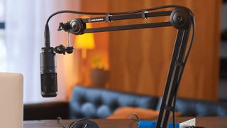 A boom mic stand from Audio-Technica holds a mic near a laptop for podcast recording.