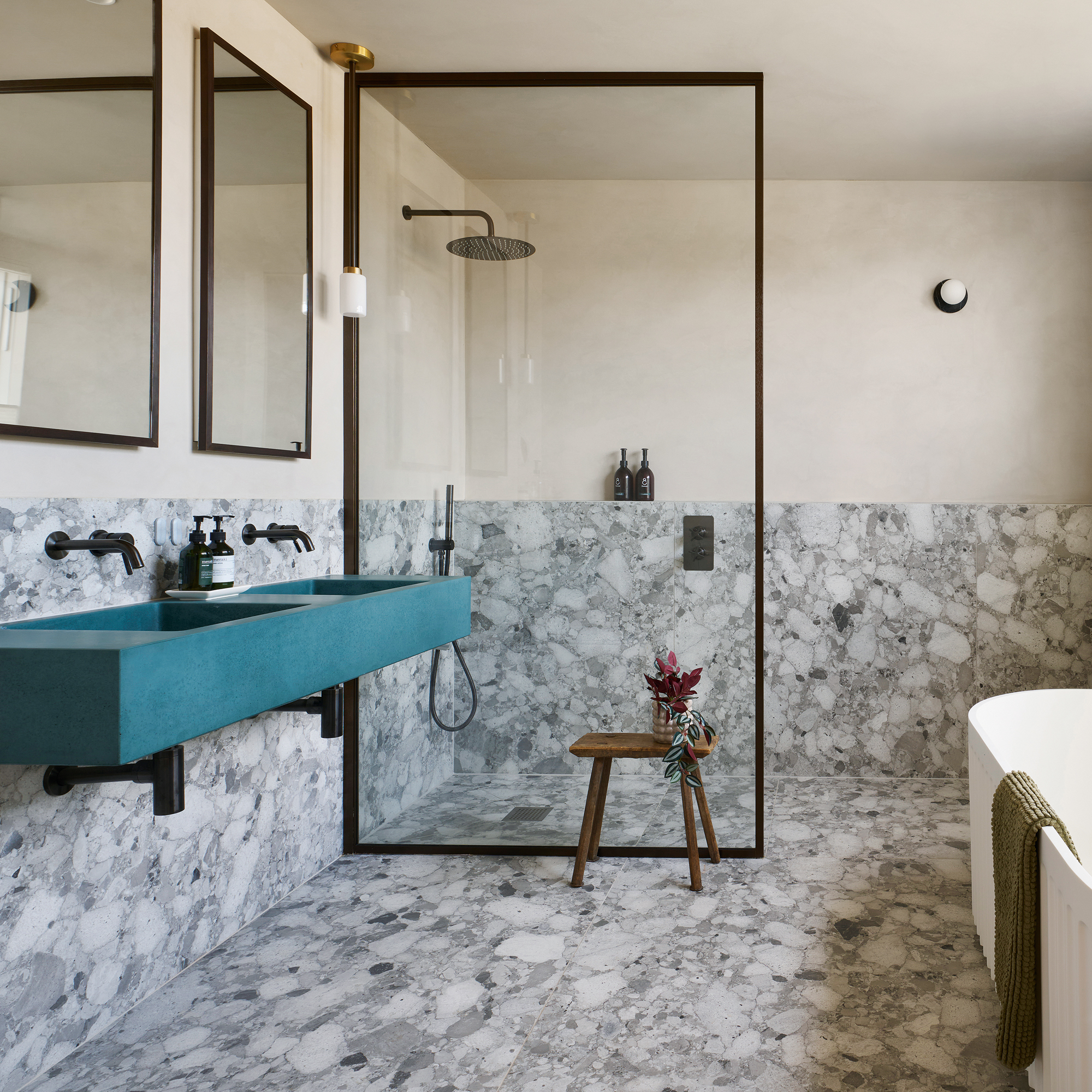 bathroom with glass shower panel, stone flooring and blue/green double basin