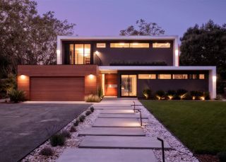 Asymmetrical front yard walkway ideas shown at dusk leading to a modern house.