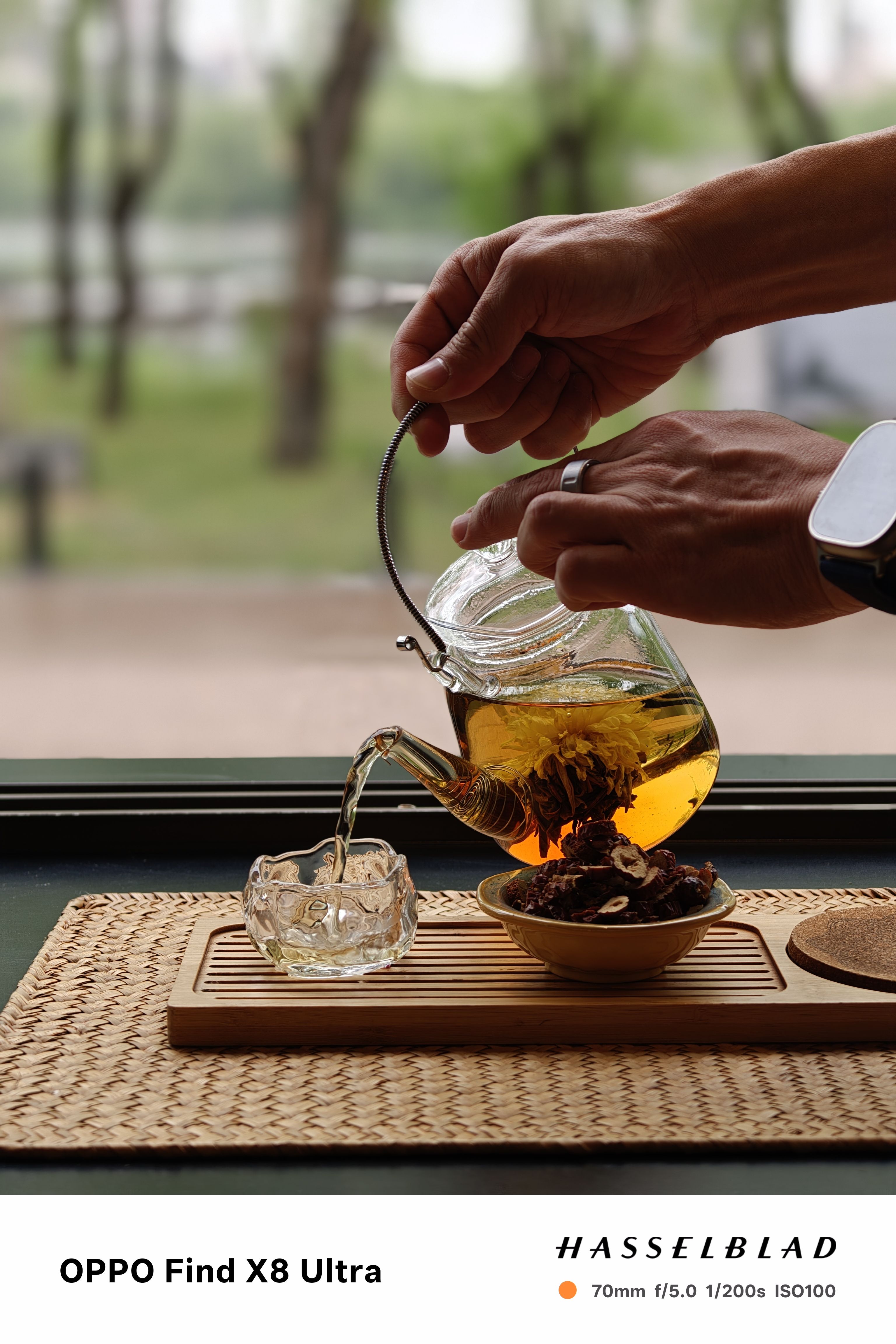 A person pouring tea from a glass teapot into a cup