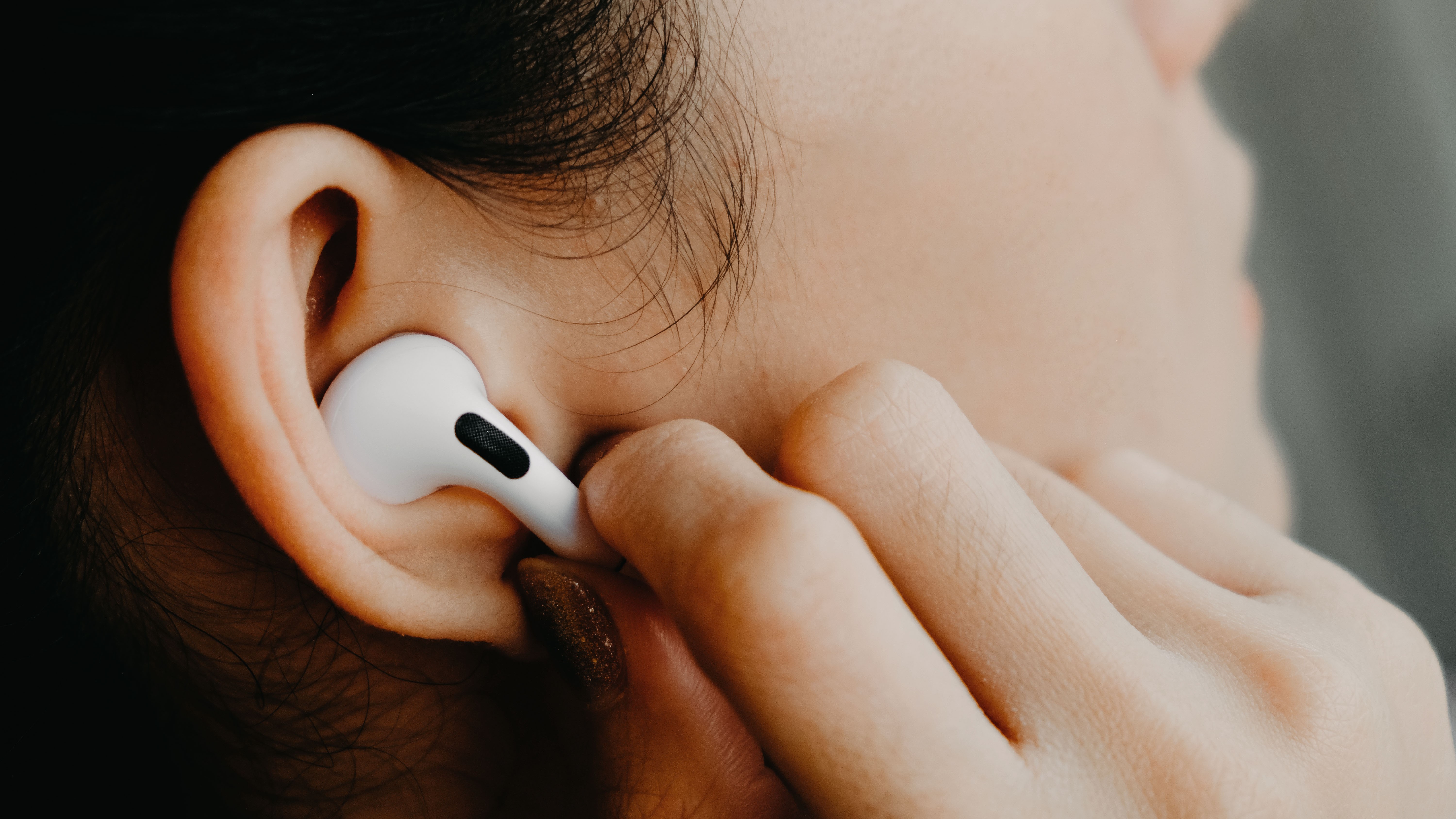 A photo of a woman putting an Apple AirPod into her ear