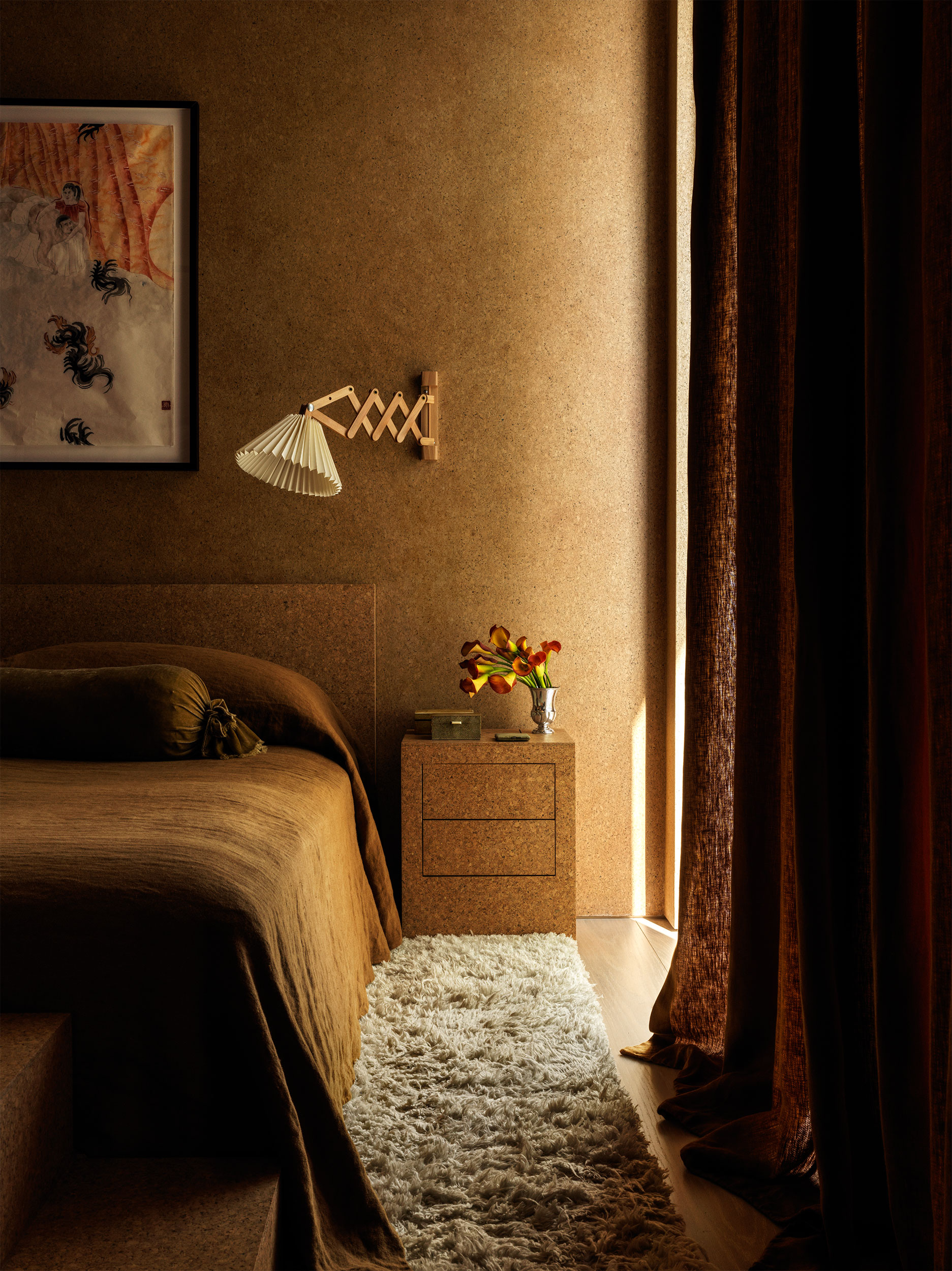 A bedroom with a fluffy carpet, ochre bedding and a wall-installed lamp