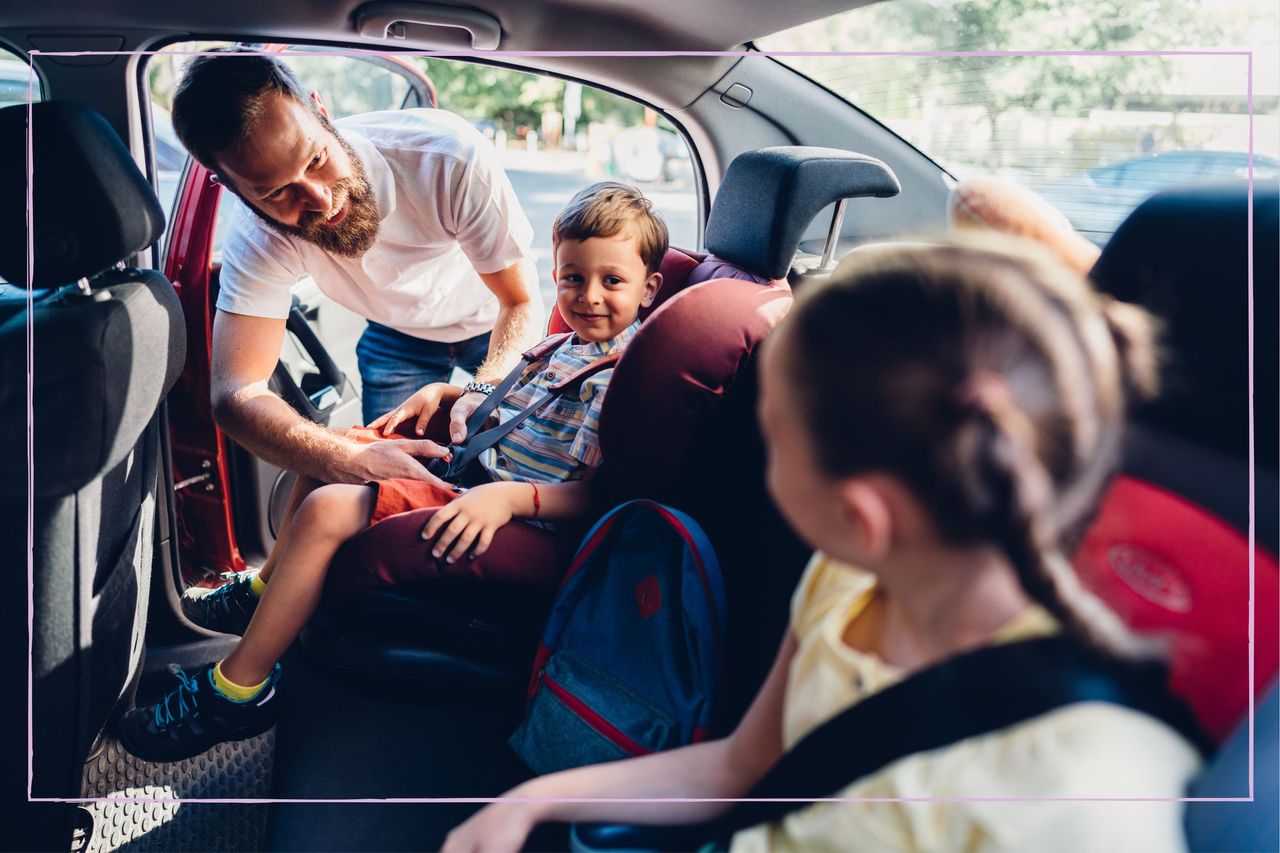 Dad getting kids into car seats in back of car