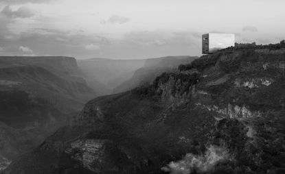 A aerial view of mountains with a rectangular grey container at the top 