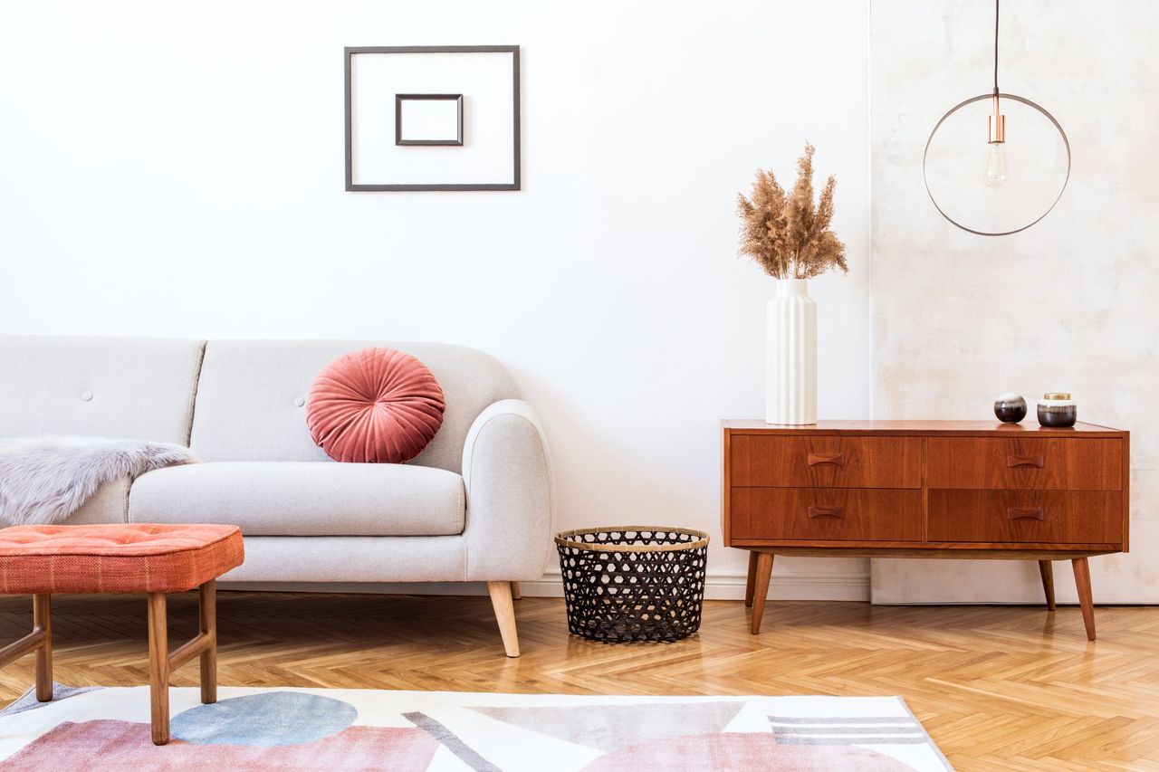 A living room with a grey sofa with a pink cushion and a pink and grey carpet