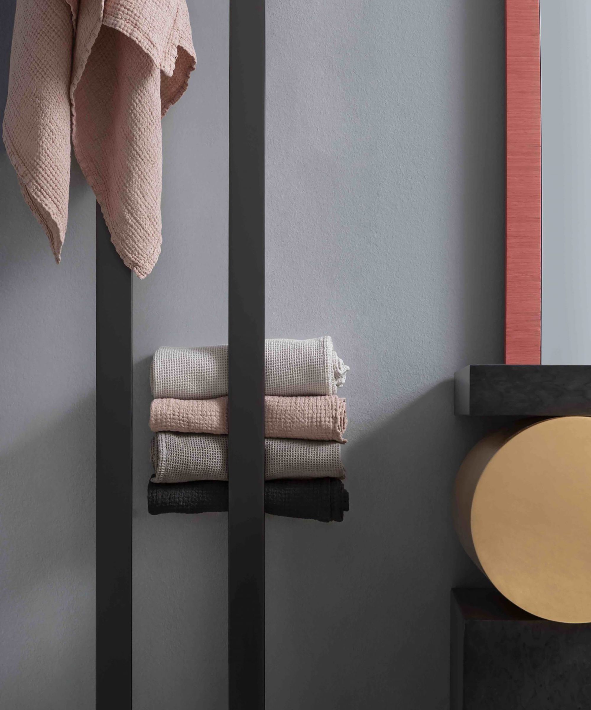Modern radiator doubles as a sleek towel rail, with neatly folded linens adding warmth and texture to the space.