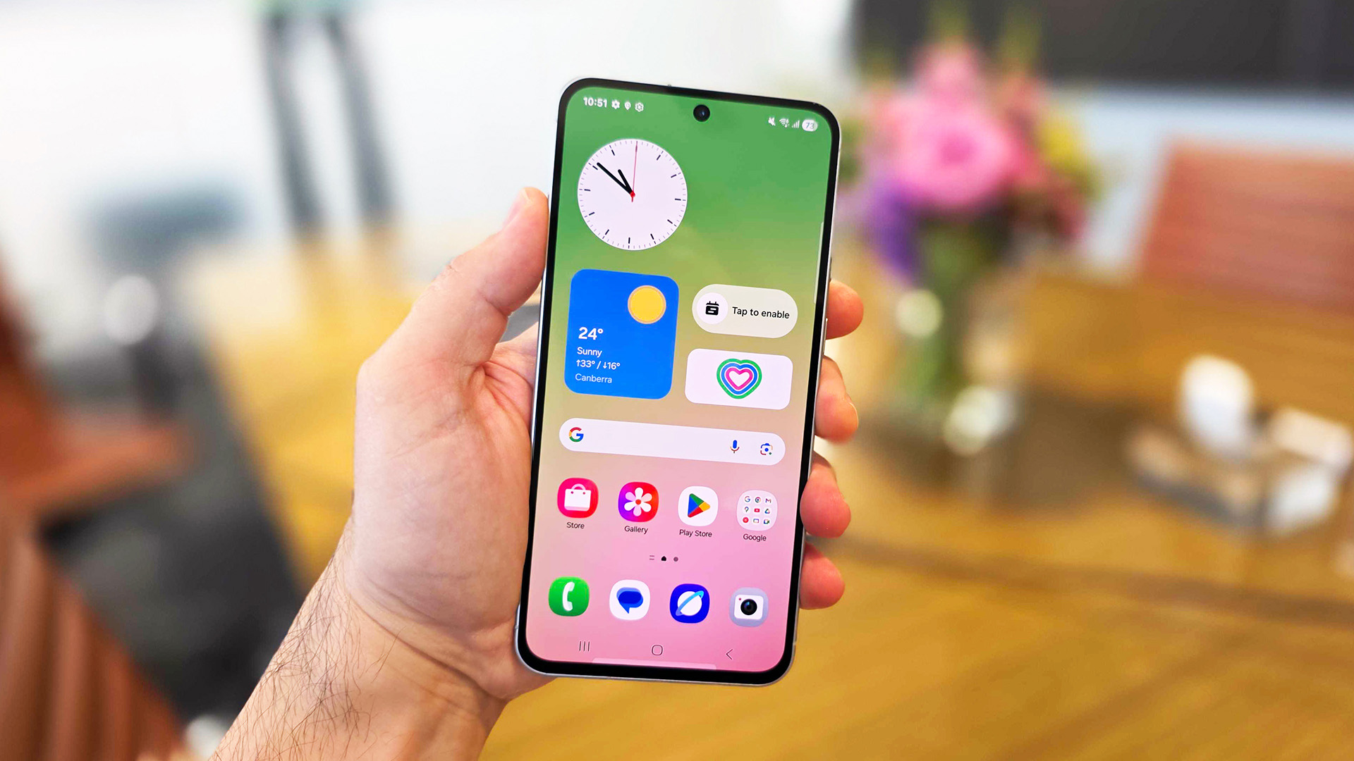 In-hand image of the Samsung Galaxy A56 handset with view of its home screen.