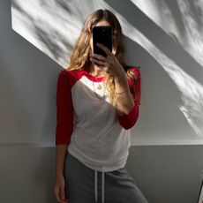 Angie wears a grey t-shirt, cream jumper, blue jeans