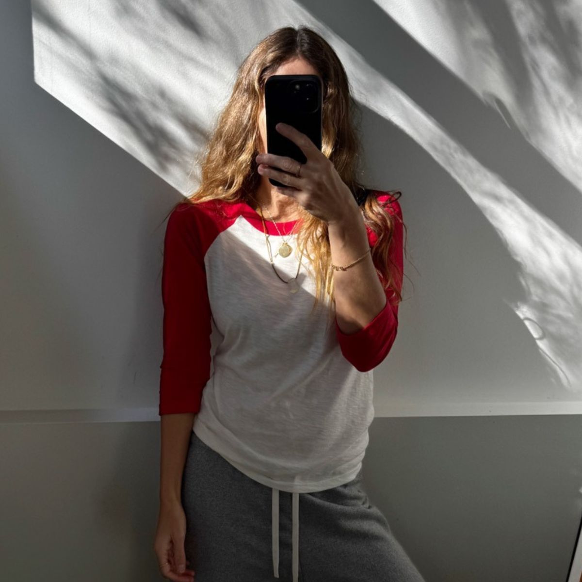 Angie wears a grey t-shirt, cream jumper, blue jeans