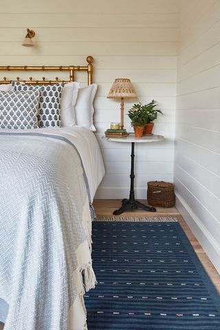 bedroom with white and blue bedding and patterned blue rug