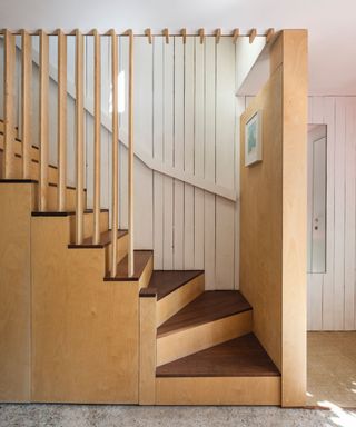 A stairwell with dark wood detailing and light plywood sides