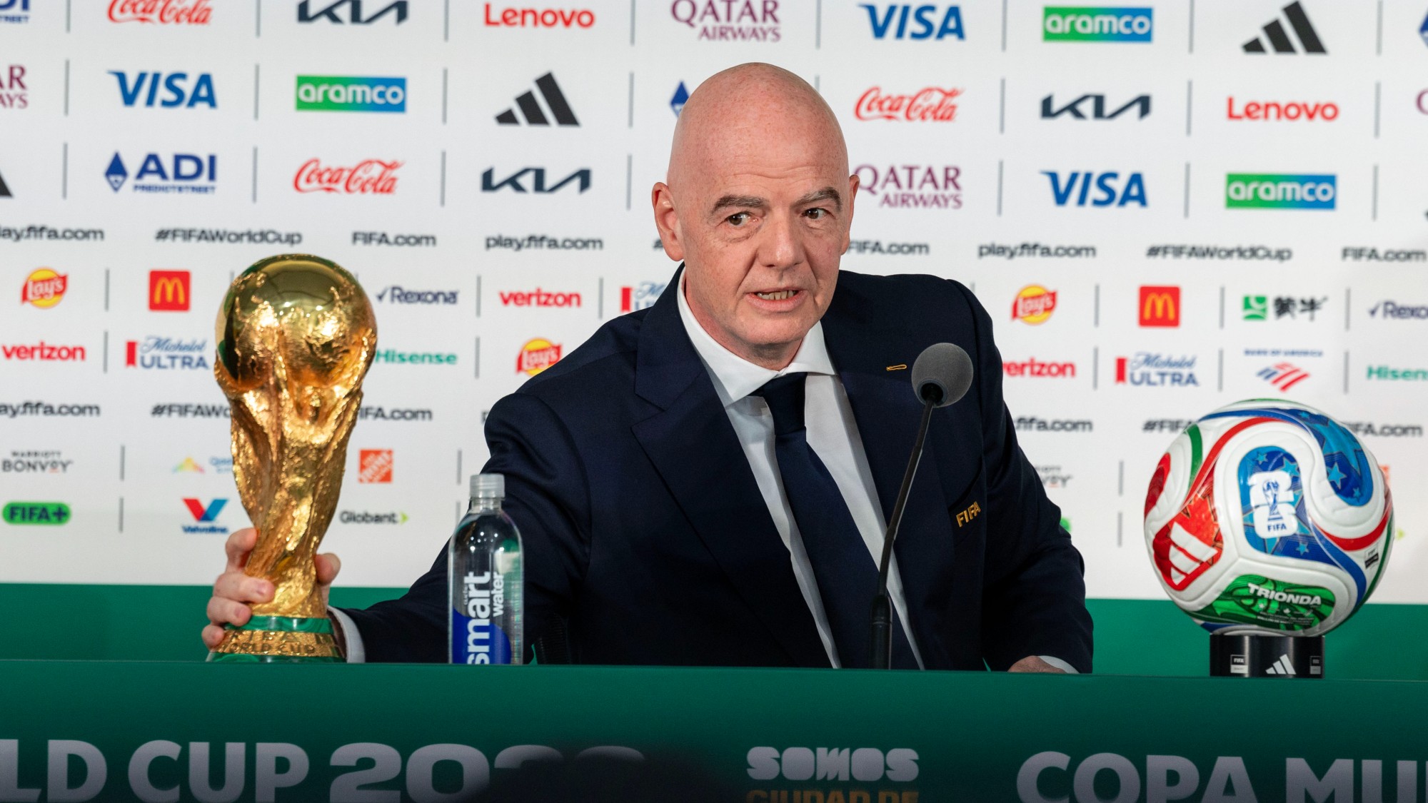 Infantino at a press conference with the world cup trophy and tournament ball