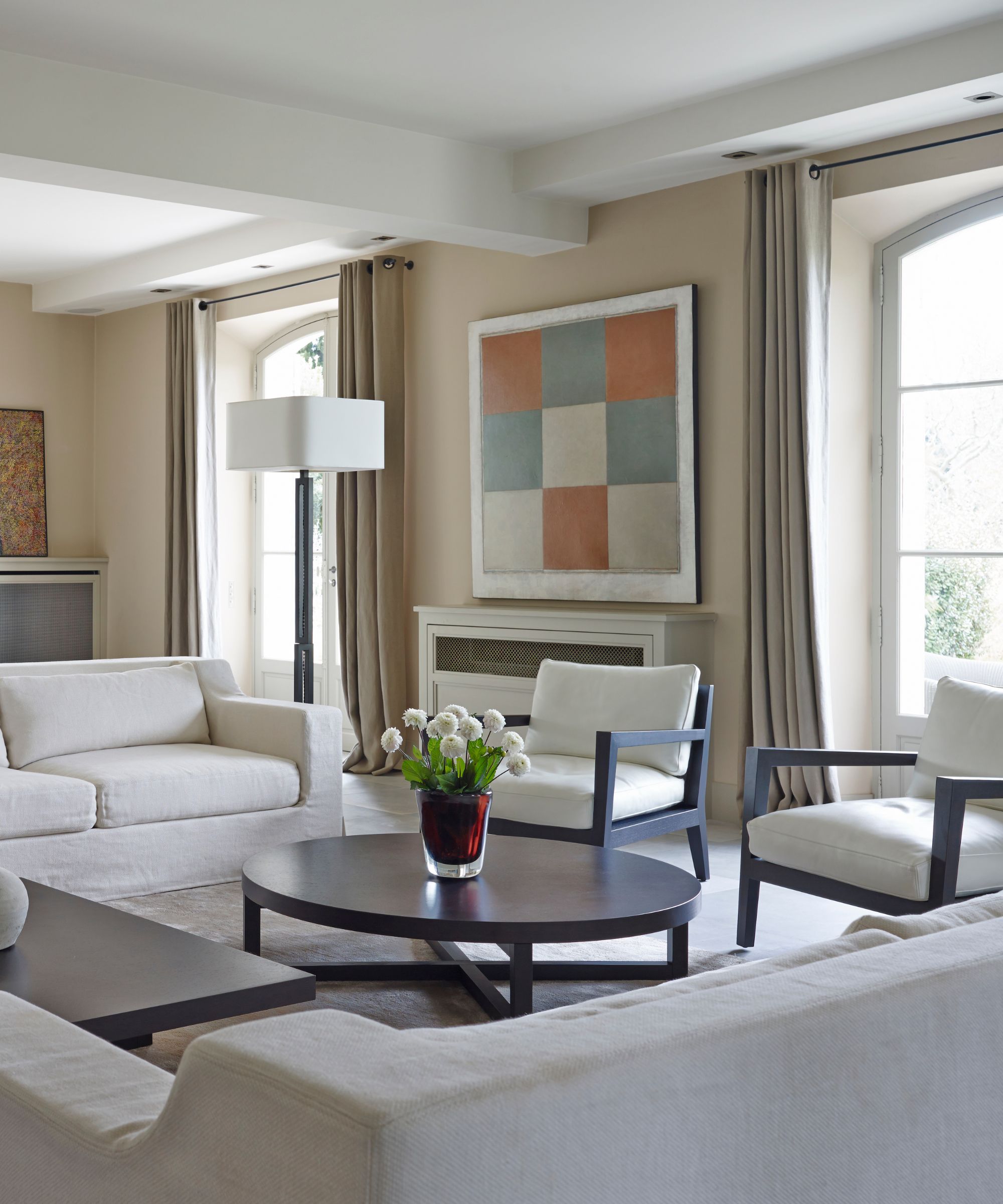 Neutral living room with white seating and a black oval coffee table