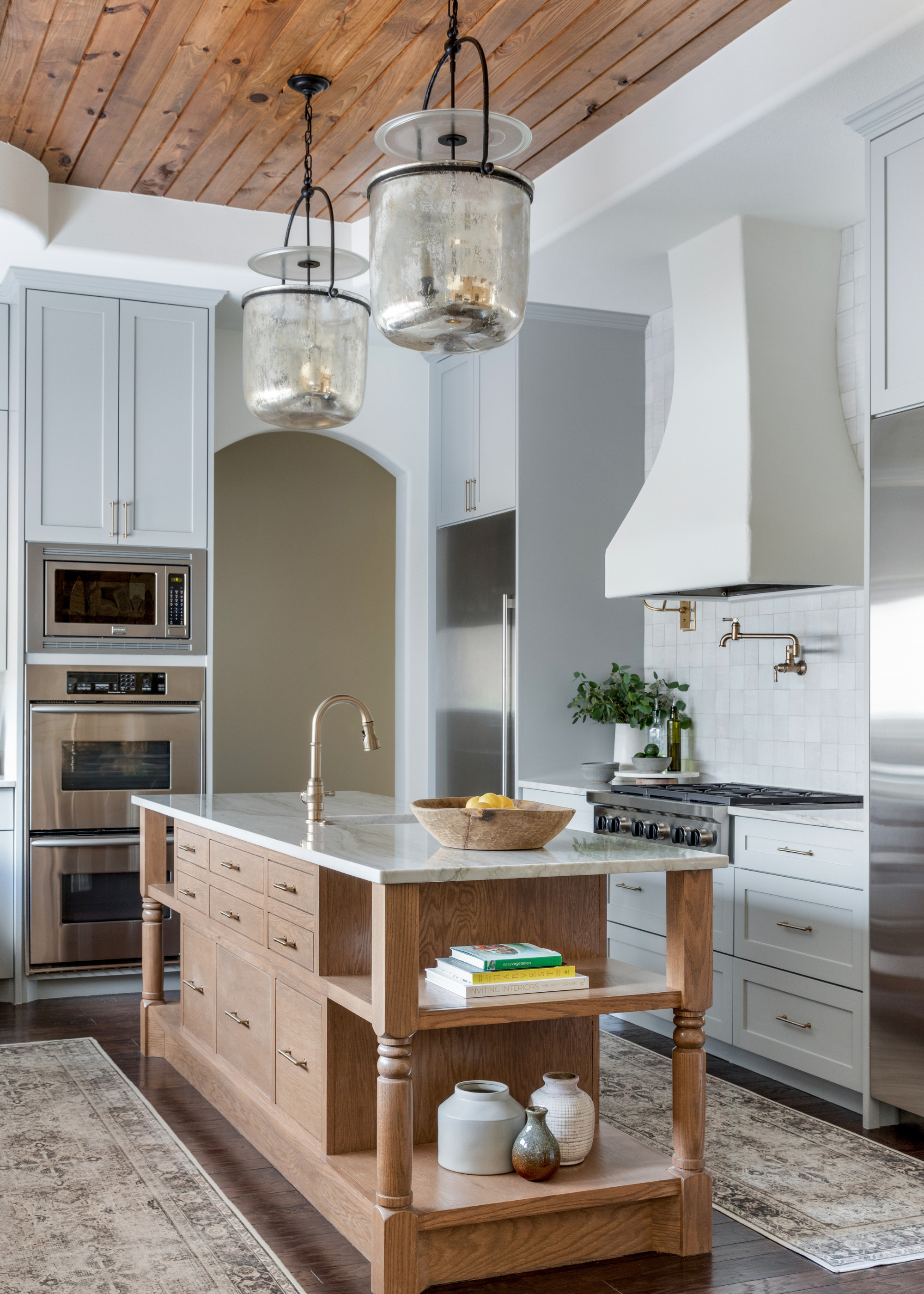 A pale blue traditional kitchen with a timber island, all in a white setting