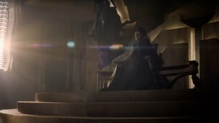 Valya Harkonnen sitting on a throne in Dune: Prophecy. She is wearing a black dress and a black veil.