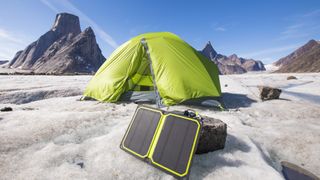 Solar panel charger with tent in background at remote campsite