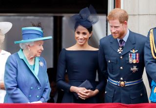 Queen Elizabeth II, Meghan, Duchess of Sussex and Prince Harry, Duke of Sussex watch a flypast to mark the centenary of the Royal Air Force