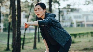 Young woman checking GPS watch while running in park