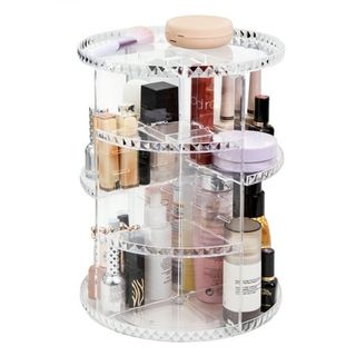 A tall, four tier clear round plastic makeup organizer, with products on the shelved areas that are split into quadrants.